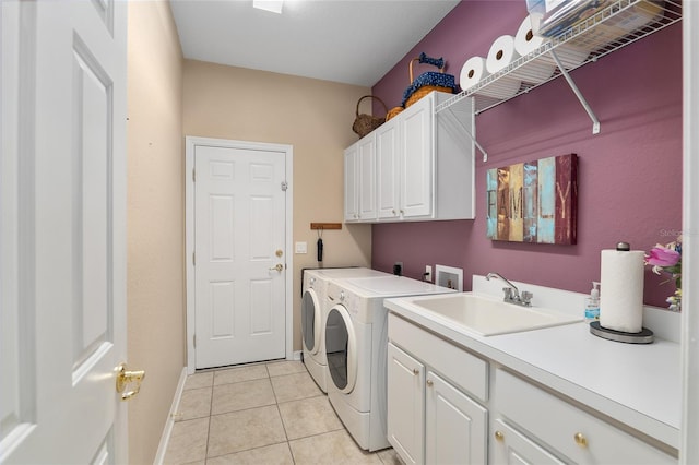 clothes washing area with sink, light tile patterned flooring, washer and dryer, and cabinets