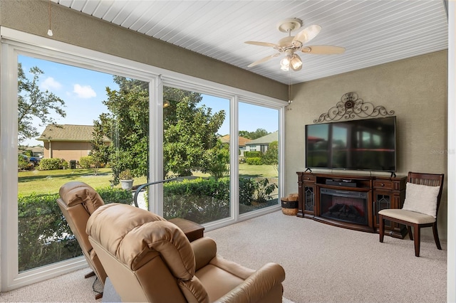 sunroom featuring ceiling fan and a fireplace