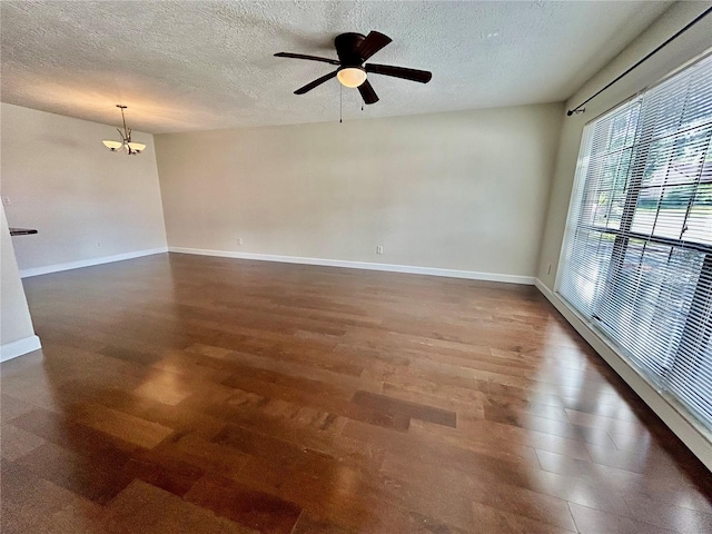 empty room with dark hardwood / wood-style floors, a textured ceiling, and ceiling fan with notable chandelier