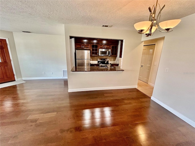 unfurnished living room with dark hardwood / wood-style floors, a textured ceiling, and an inviting chandelier