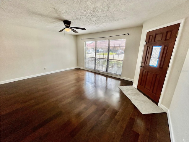 foyer entrance with dark hardwood / wood-style flooring, a textured ceiling, and ceiling fan