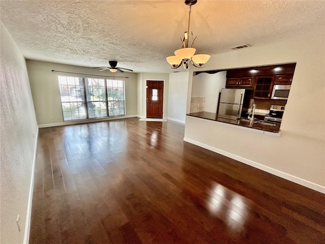 unfurnished living room with sink, a textured ceiling, dark hardwood / wood-style floors, and ceiling fan with notable chandelier