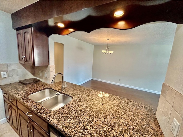 kitchen with dark stone countertops, backsplash, sink, and light wood-type flooring