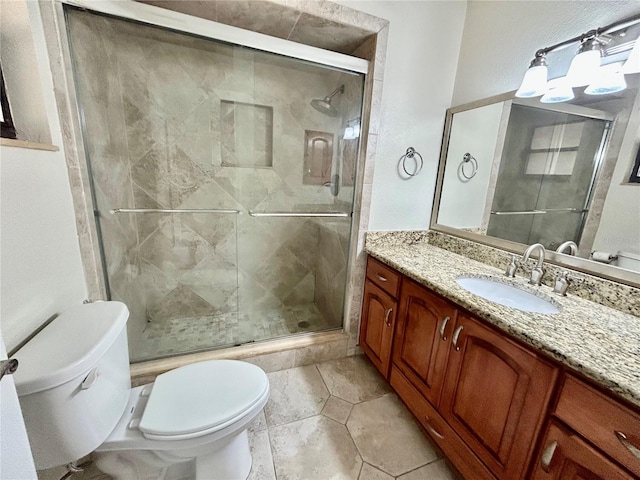 bathroom with a shower with shower door, vanity, toilet, and tile patterned floors