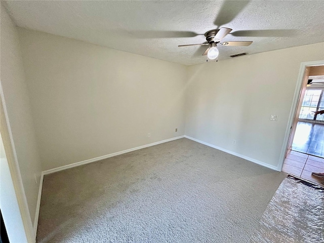 carpeted spare room featuring ceiling fan and a textured ceiling