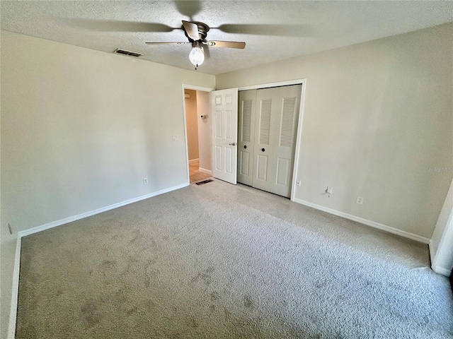 unfurnished bedroom with a textured ceiling, carpet flooring, ceiling fan, and a closet