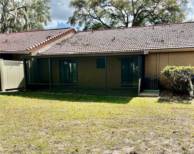 back of property featuring central air condition unit, a sunroom, and a yard