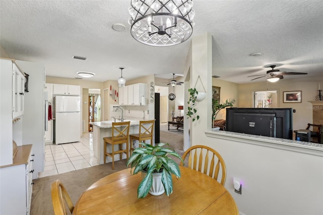 tiled dining space with ceiling fan with notable chandelier and a textured ceiling