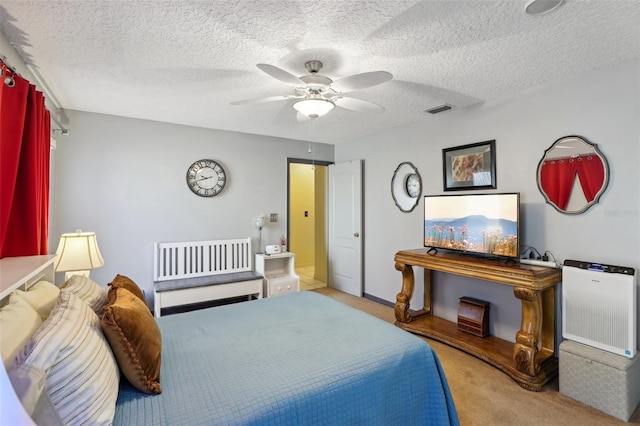 bedroom featuring a textured ceiling, light colored carpet, and ceiling fan