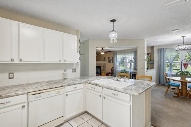 kitchen featuring kitchen peninsula, white dishwasher, ceiling fan, pendant lighting, and white cabinets