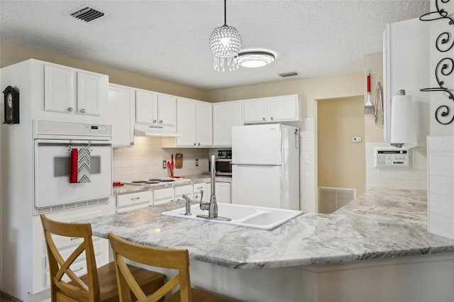 kitchen featuring kitchen peninsula, tasteful backsplash, a breakfast bar, white appliances, and white cabinetry