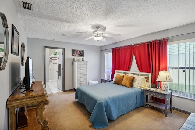 bedroom featuring multiple windows, a textured ceiling, light colored carpet, and ceiling fan