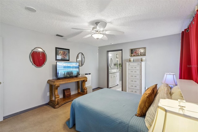 bedroom with a textured ceiling, ceiling fan, light carpet, and connected bathroom