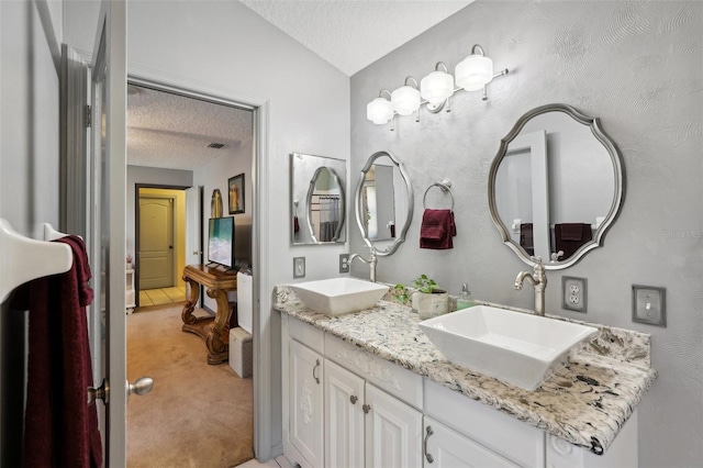 bathroom with vaulted ceiling, vanity, and a textured ceiling