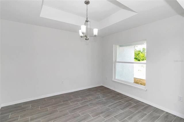 unfurnished room with dark wood-type flooring, a raised ceiling, and a notable chandelier