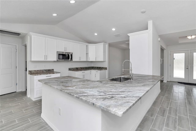 kitchen featuring white cabinets, lofted ceiling, and sink