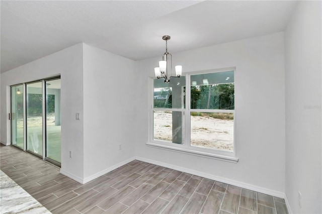 unfurnished room featuring a notable chandelier, light hardwood / wood-style floors, and plenty of natural light