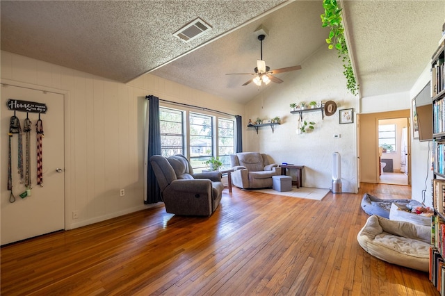 living room featuring ceiling fan, a textured ceiling, lofted ceiling, and hardwood / wood-style floors