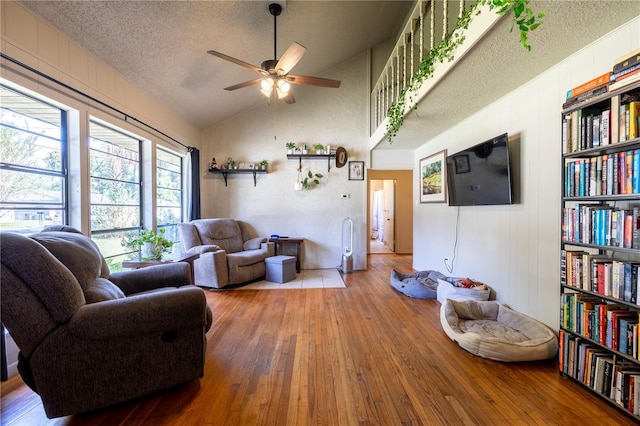 living room featuring a textured ceiling, vaulted ceiling, hardwood / wood-style flooring, and ceiling fan