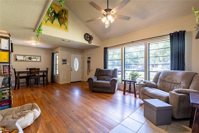 living room featuring a textured ceiling, wood-type flooring, high vaulted ceiling, and ceiling fan