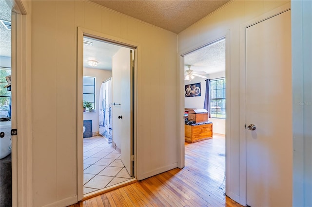 hall with crown molding, a textured ceiling, and light wood-type flooring