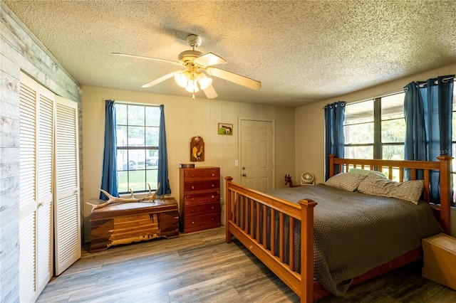 bedroom with hardwood / wood-style floors, a textured ceiling, and ceiling fan