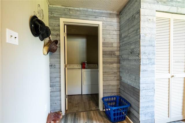 hallway with wooden walls, washer and dryer, a textured ceiling, and hardwood / wood-style flooring