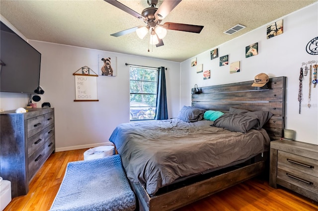 bedroom with light hardwood / wood-style flooring, a textured ceiling, and ceiling fan