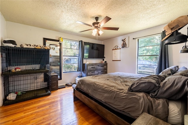 bedroom with ceiling fan, hardwood / wood-style flooring, and a textured ceiling