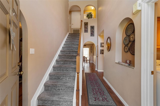 stairs with wood-type flooring and a high ceiling