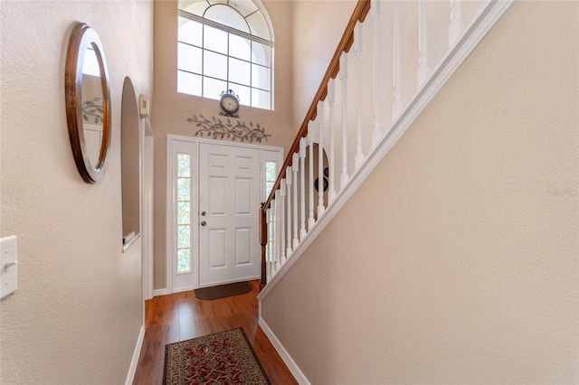 entryway with hardwood / wood-style floors and a towering ceiling