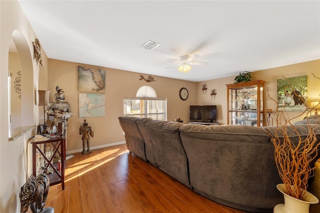 living room featuring dark wood-type flooring and ceiling fan