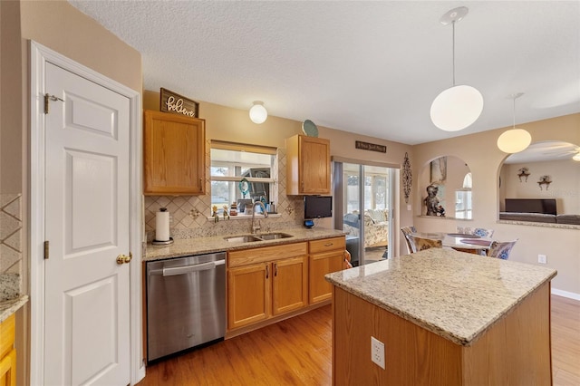 kitchen with stainless steel dishwasher, a center island, pendant lighting, and a healthy amount of sunlight