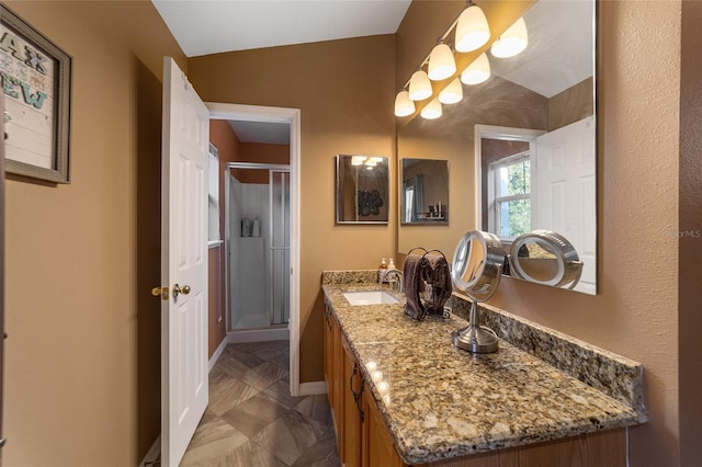 bathroom featuring a shower with door, vanity, and vaulted ceiling