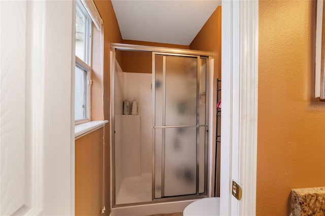 bathroom with toilet, walk in shower, and a textured ceiling