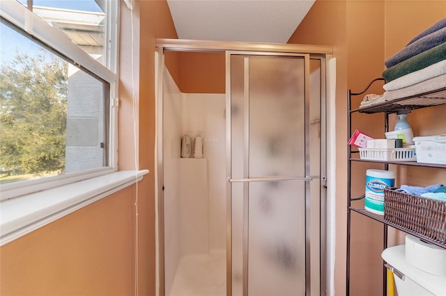 bathroom featuring a textured ceiling, toilet, and an enclosed shower