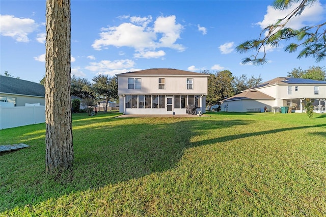 rear view of house with a lawn and a sunroom