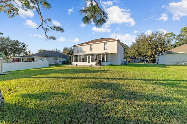 back of house featuring a lawn and a sunroom