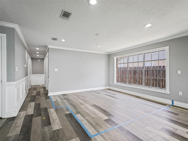 unfurnished room featuring dark wood-type flooring, crown molding, and a textured ceiling