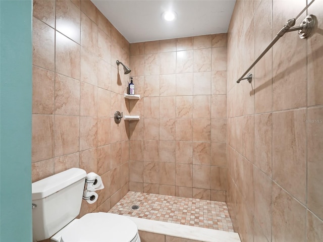 bathroom with tile walls, a tile shower, and toilet