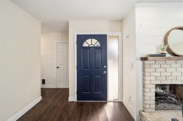 foyer entrance with dark wood-type flooring and a fireplace