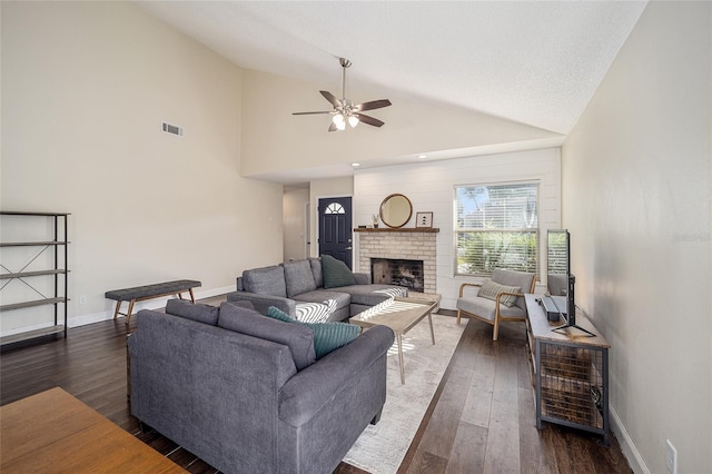 living room with a brick fireplace, dark hardwood / wood-style floors, high vaulted ceiling, and ceiling fan