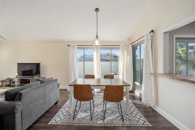 dining space with a textured ceiling, lofted ceiling, plenty of natural light, and dark hardwood / wood-style floors