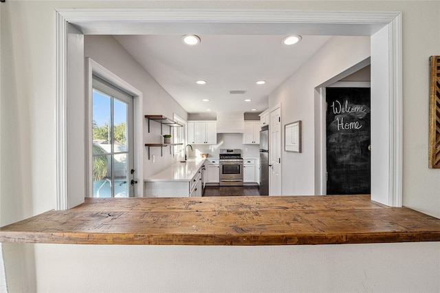 kitchen featuring stainless steel appliances, sink, kitchen peninsula, and white cabinets