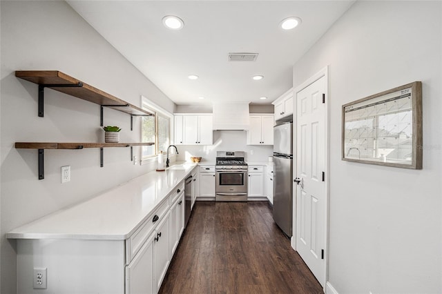 kitchen featuring dark wood-type flooring, custom range hood, stainless steel appliances, sink, and white cabinetry