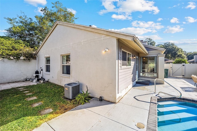 view of side of home with central AC unit, a patio, and a fenced in pool