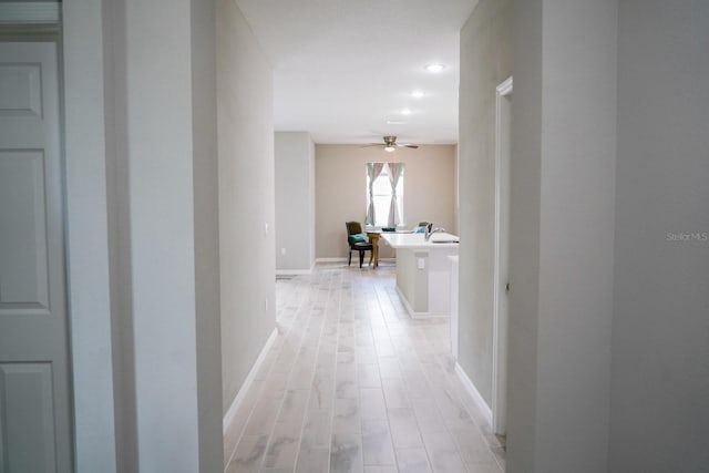 hallway featuring light wood-style floors and baseboards