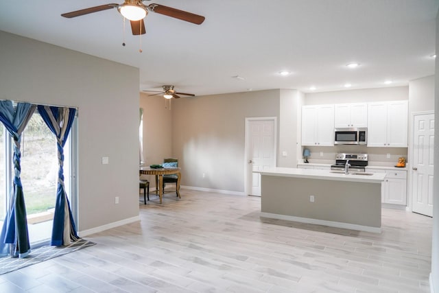 kitchen featuring an island with sink, appliances with stainless steel finishes, light countertops, and white cabinets