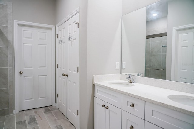 full bath featuring double vanity, a sink, and a shower stall