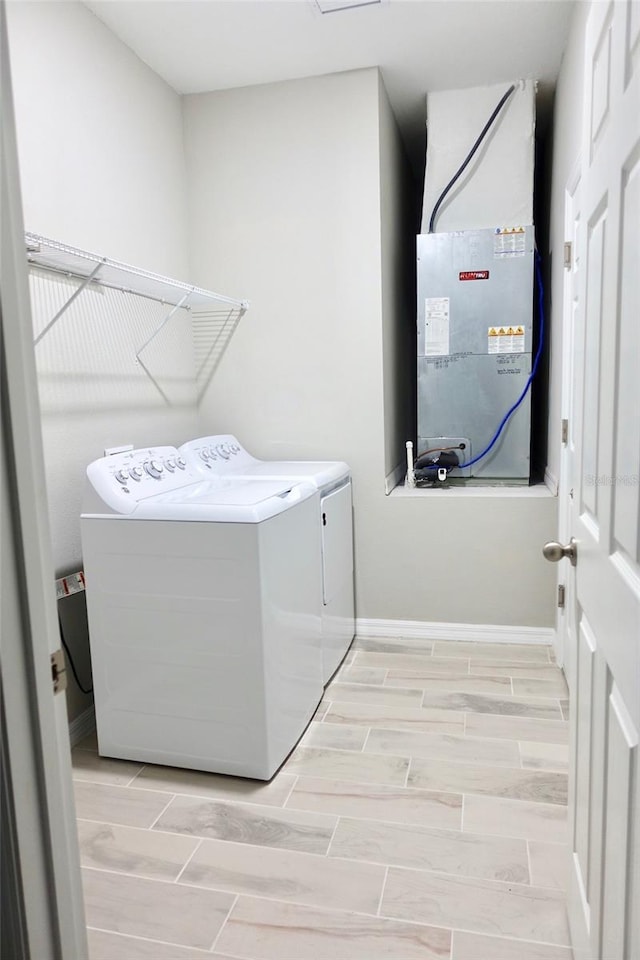 washroom with laundry area, baseboards, heating unit, wood tiled floor, and separate washer and dryer